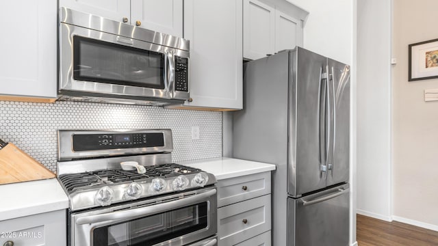 kitchen featuring stainless steel appliances, light countertops, backsplash, baseboards, and dark wood-style flooring