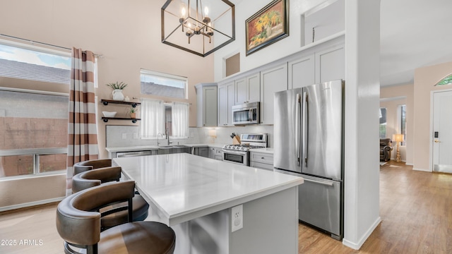 kitchen featuring appliances with stainless steel finishes, open shelves, a sink, a high ceiling, and a kitchen bar