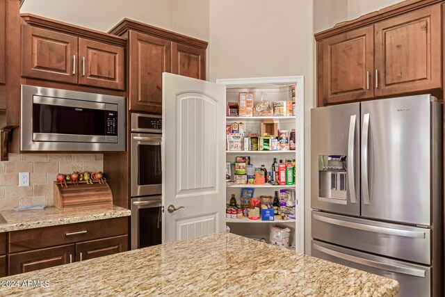 kitchen with light stone counters, backsplash, and appliances with stainless steel finishes