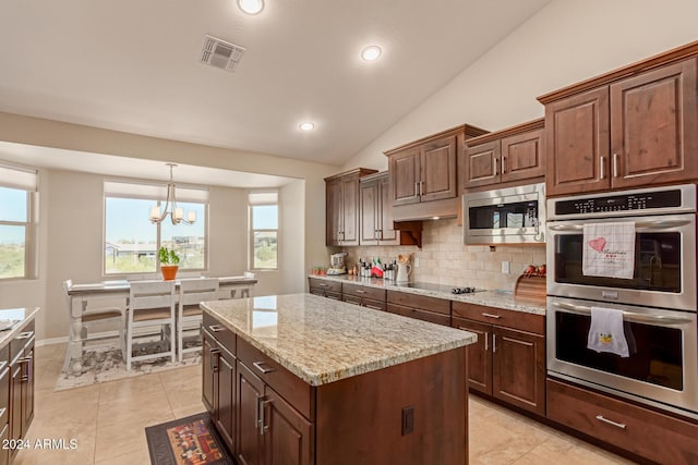 kitchen featuring a center island, hanging light fixtures, vaulted ceiling, a notable chandelier, and stainless steel appliances