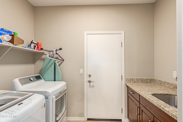 laundry room with washer and clothes dryer, cabinets, and sink