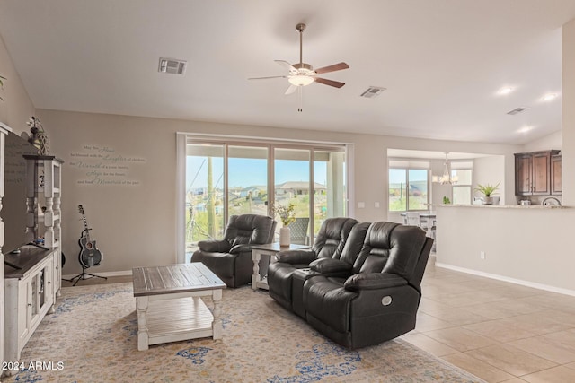 living room with vaulted ceiling, light tile patterned floors, and ceiling fan with notable chandelier