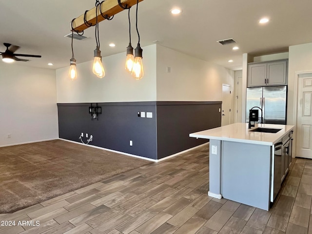 kitchen featuring gray cabinetry, sink, decorative light fixtures, stainless steel fridge with ice dispenser, and a center island with sink