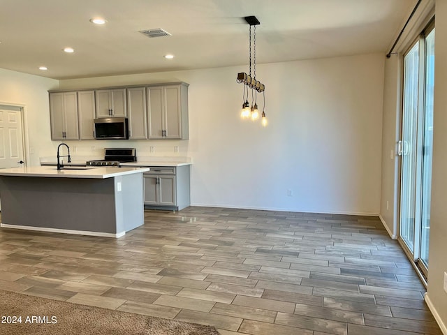 kitchen featuring light hardwood / wood-style floors, black range, decorative light fixtures, and gray cabinetry