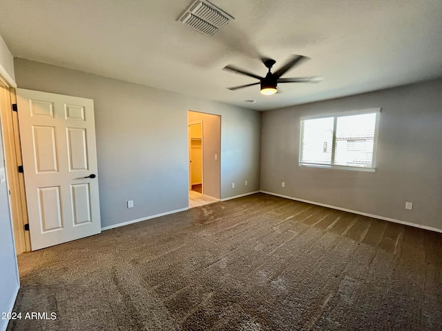 unfurnished bedroom with a spacious closet, carpet flooring, and ceiling fan