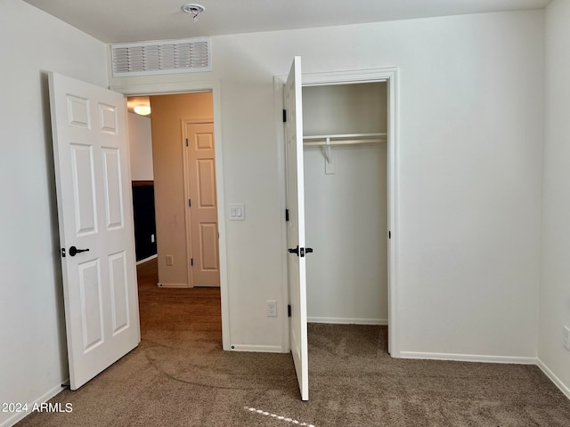 unfurnished bedroom with dark carpet and a closet