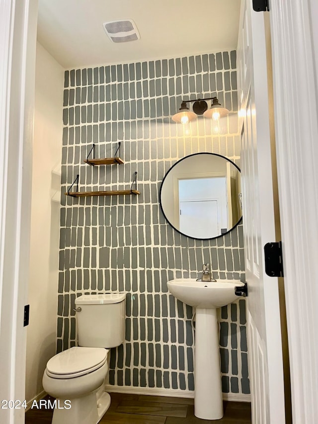 bathroom with toilet, hardwood / wood-style flooring, sink, and tile walls