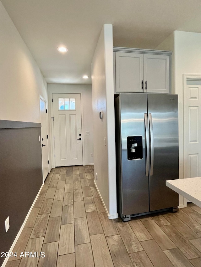 kitchen featuring stainless steel fridge with ice dispenser, white cabinetry, and light hardwood / wood-style floors