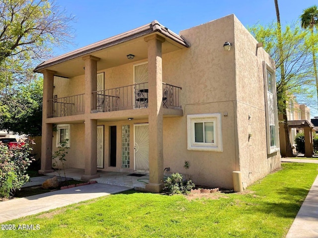 back of house featuring a lawn and a balcony