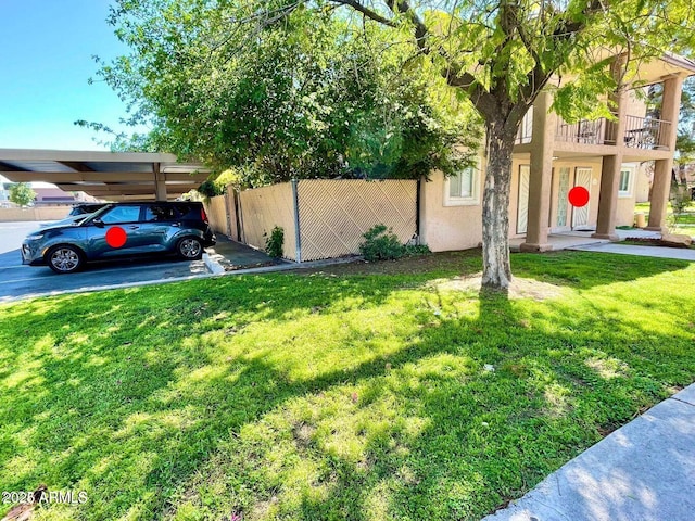 view of yard with a carport and a balcony