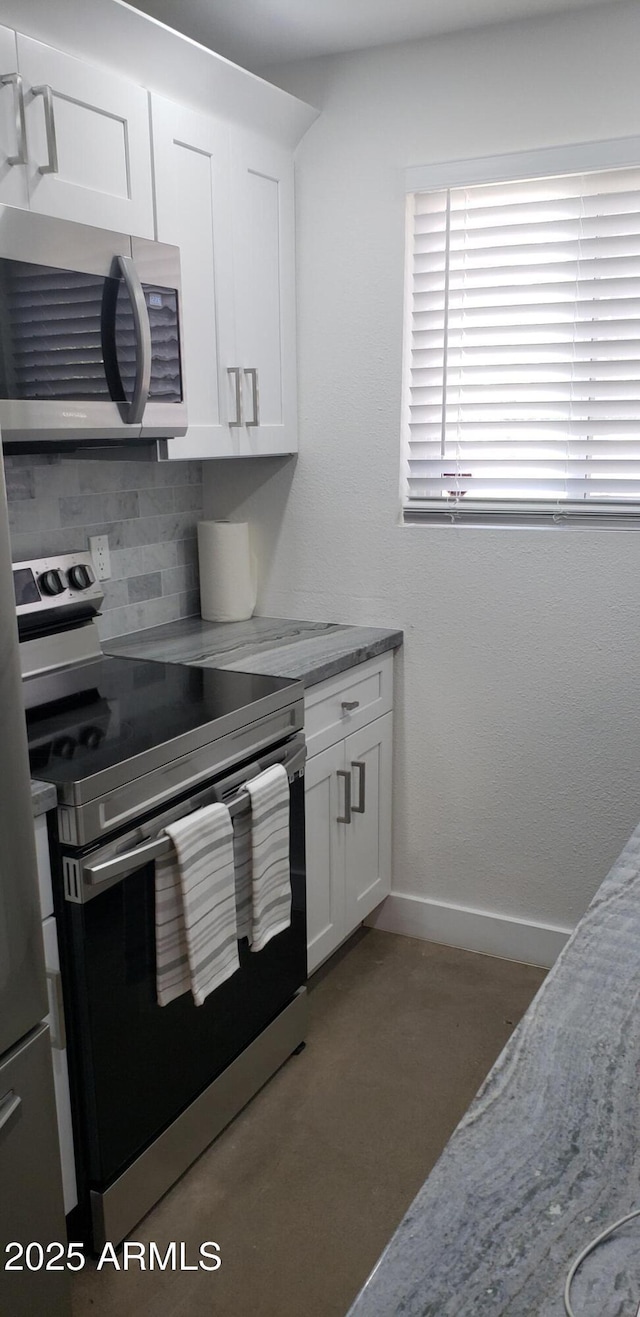 kitchen with white cabinetry, light stone countertops, decorative backsplash, and stainless steel appliances