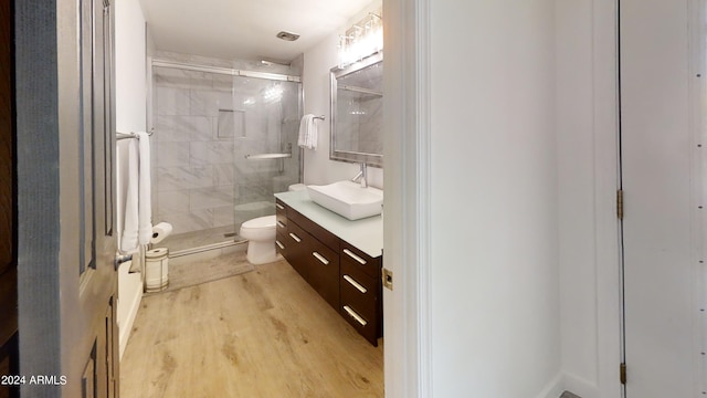 bathroom featuring vanity, hardwood / wood-style floors, a shower with shower door, and toilet