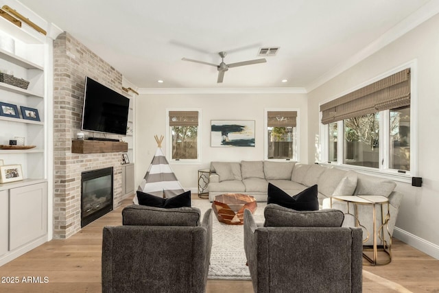 living room featuring built in shelves, ornamental molding, and light wood-type flooring