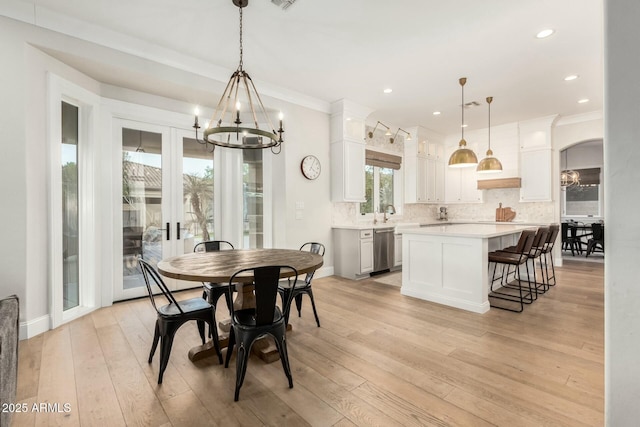 dining space with a notable chandelier, crown molding, and light hardwood / wood-style floors