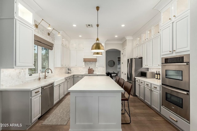 kitchen featuring decorative light fixtures, a center island, white cabinets, and appliances with stainless steel finishes