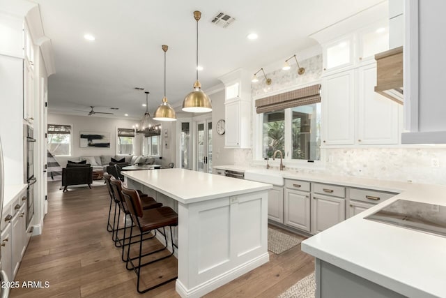 kitchen with a kitchen bar, sink, a kitchen island, decorative backsplash, and white cabinets