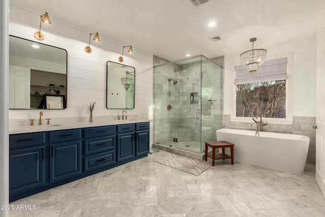 bathroom featuring shower with separate bathtub, tile walls, vanity, and a chandelier