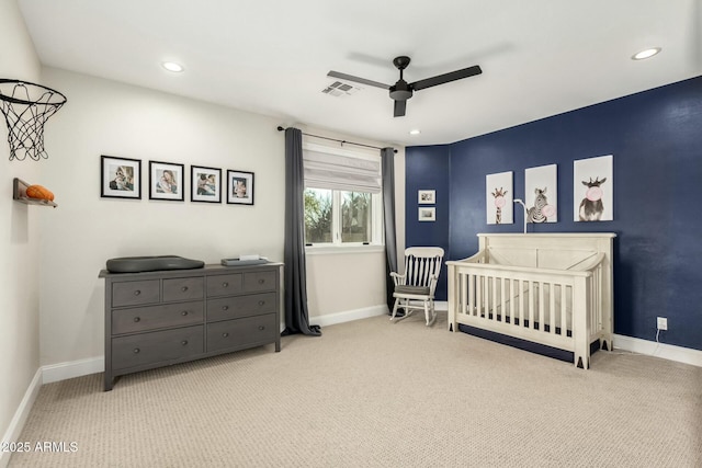 carpeted bedroom featuring a nursery area and ceiling fan