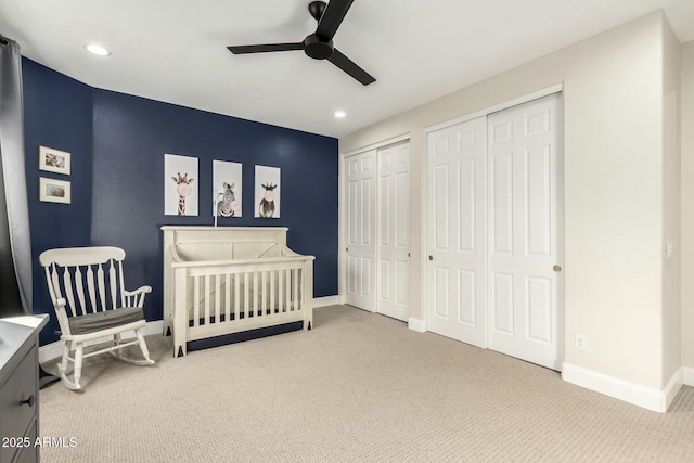 carpeted bedroom featuring ceiling fan and multiple closets