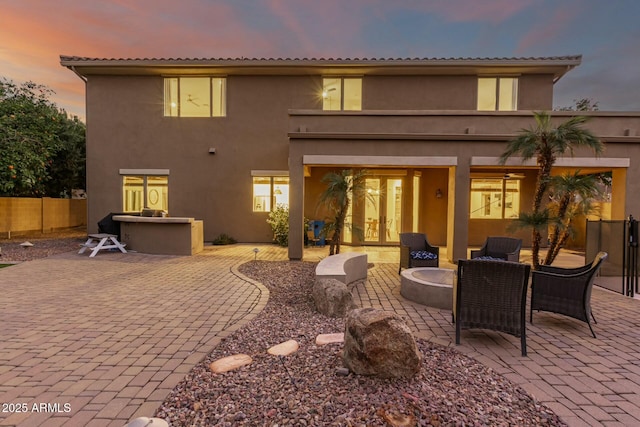 back house at dusk featuring a patio area and a fire pit