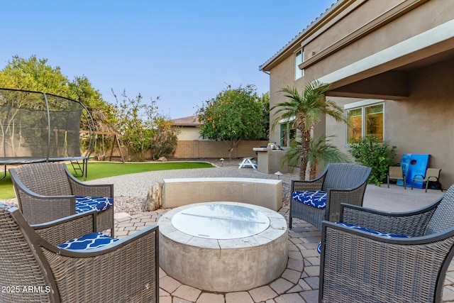 view of patio featuring a trampoline and an outdoor fire pit