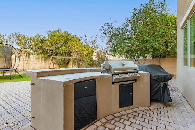 view of patio featuring a trampoline, a grill, and exterior kitchen