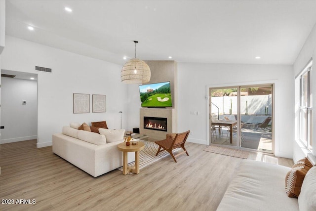 living room featuring light hardwood / wood-style flooring, a wealth of natural light, and lofted ceiling