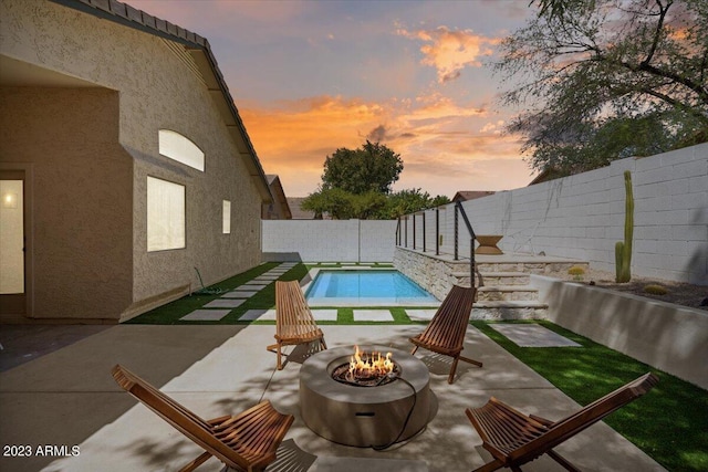 pool at dusk with a patio and an outdoor fire pit