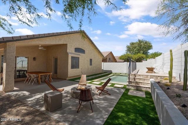 back of property with a patio, a fenced in pool, ceiling fan, and an outdoor fire pit