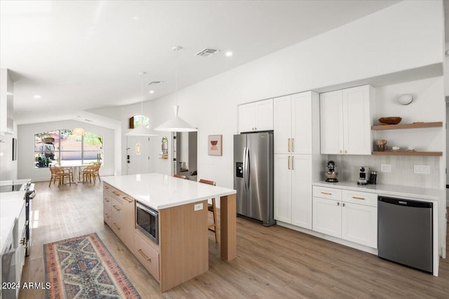 kitchen featuring a center island, decorative light fixtures, light hardwood / wood-style floors, white cabinetry, and stainless steel appliances