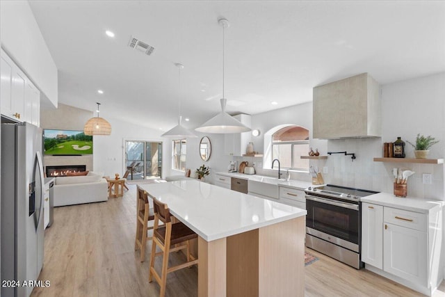 kitchen with white cabinets, backsplash, a center island, and stainless steel appliances