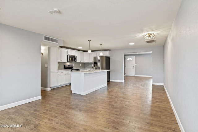 kitchen featuring white cabinetry, sink, decorative light fixtures, a kitchen island with sink, and appliances with stainless steel finishes