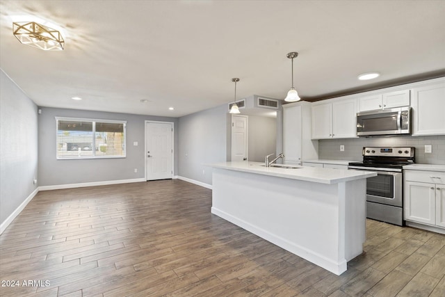 kitchen with hanging light fixtures, stainless steel appliances, decorative backsplash, a kitchen island with sink, and white cabinets