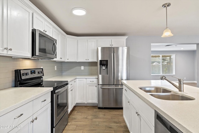 kitchen with decorative backsplash, stainless steel appliances, sink, pendant lighting, and white cabinetry