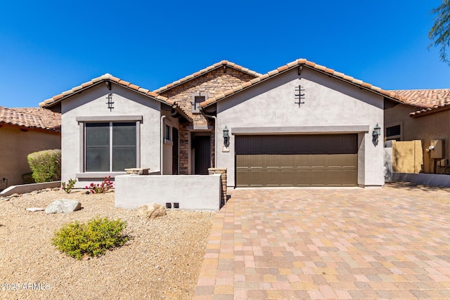 view of front of property with stucco siding, an attached garage, a tiled roof, and decorative driveway