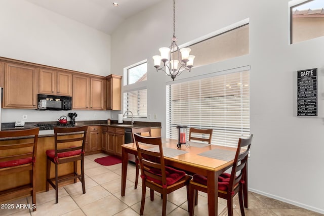 dining area with light tile patterned flooring, baseboards, a notable chandelier, and high vaulted ceiling