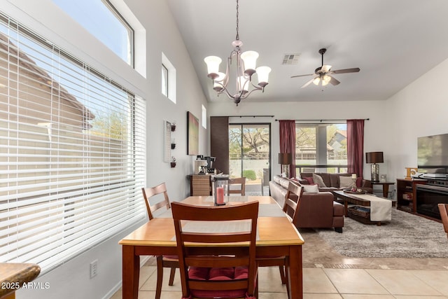 dining space with light tile patterned flooring, ceiling fan with notable chandelier, visible vents, and lofted ceiling