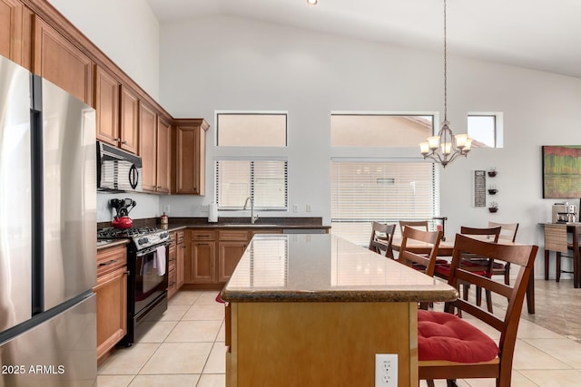 kitchen featuring a kitchen bar, a sink, black appliances, and light tile patterned flooring