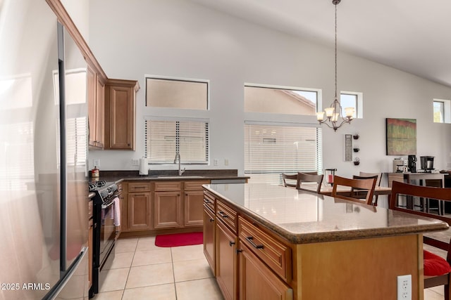 kitchen with black range with gas cooktop, lofted ceiling, light tile patterned floors, a sink, and freestanding refrigerator