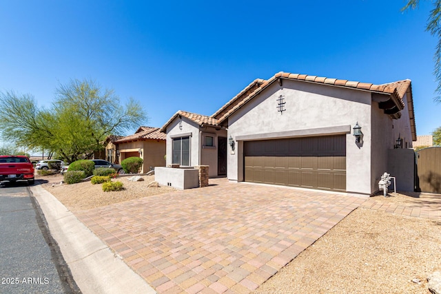 view of front of property with decorative driveway, a tile roof, stucco siding, and a garage