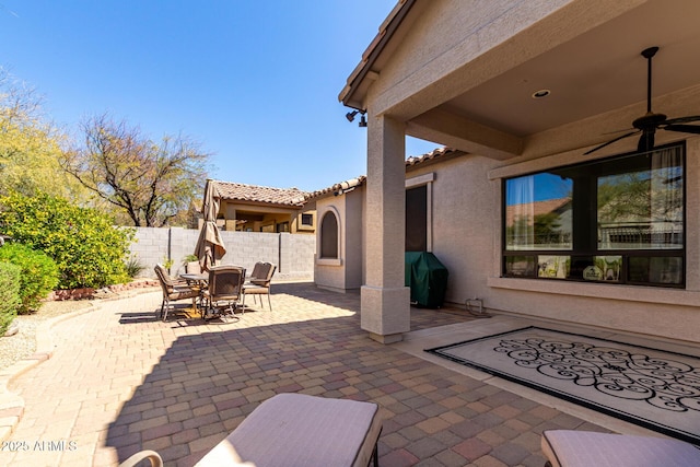 view of patio featuring outdoor dining area, area for grilling, fence, and a ceiling fan