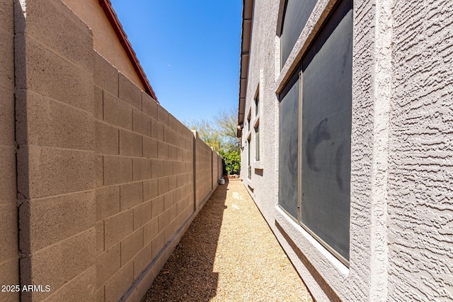 view of side of home featuring stucco siding and fence