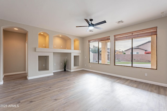 unfurnished living room featuring ceiling fan, built in features, and hardwood / wood-style floors