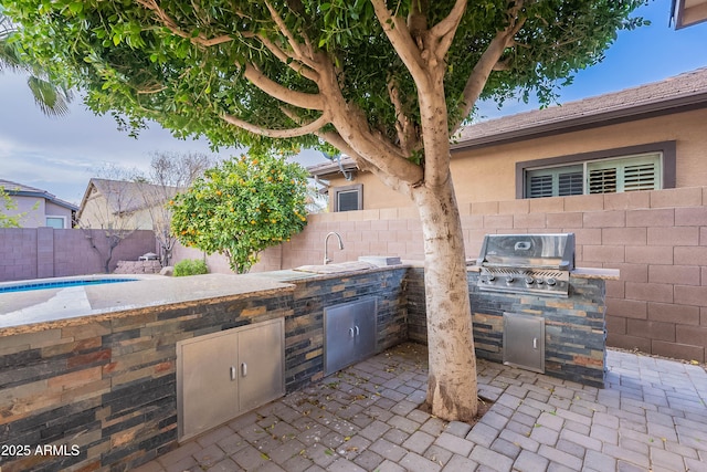 view of patio featuring sink, a fenced in pool, area for grilling, and exterior kitchen