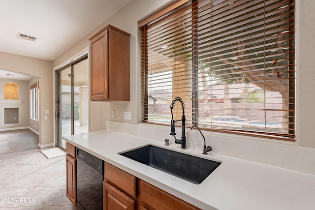 kitchen featuring light tile patterned floors, black dishwasher, plenty of natural light, and sink