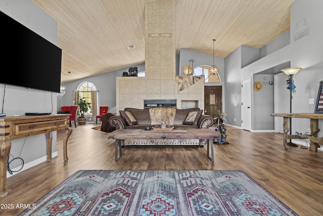 6249 E Camelot Dr, Mesa, AZ 85215 - living room featuring wooden ceiling, wood finished floors, high vaulted ceiling, a tiled fireplace, and a chandelier