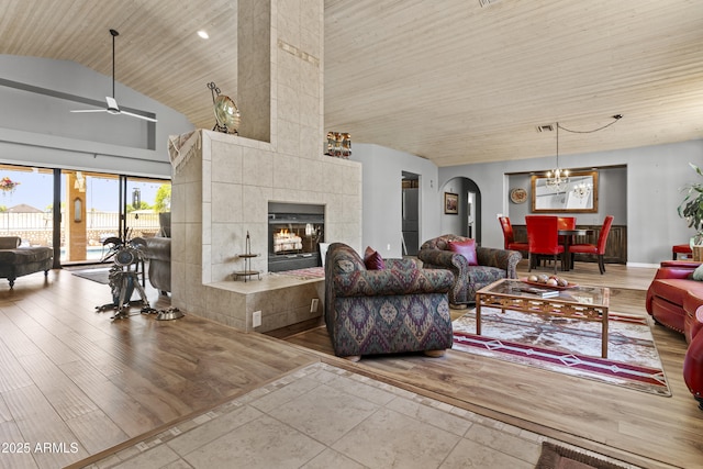 6249 E Camelot Dr, Mesa, AZ 85215 - living room featuring ceiling fan, wood ceiling, a tiled fireplace, wood finished floors, and arched walkways