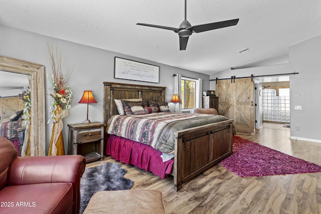 6249 E Camelot Dr, Mesa, AZ 85215 - bedroom with vaulted ceiling, a textured ceiling, wood finished floors, a barn door, and a ceiling fan