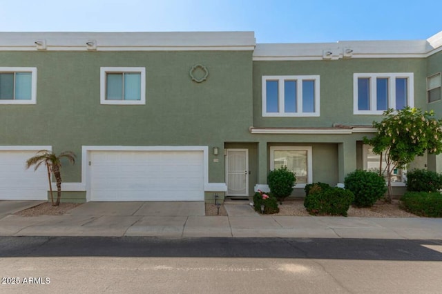 multi unit property with stucco siding, driveway, and a garage