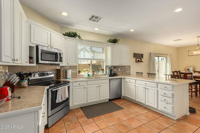 kitchen with visible vents, appliances with stainless steel finishes, a peninsula, plenty of natural light, and a sink